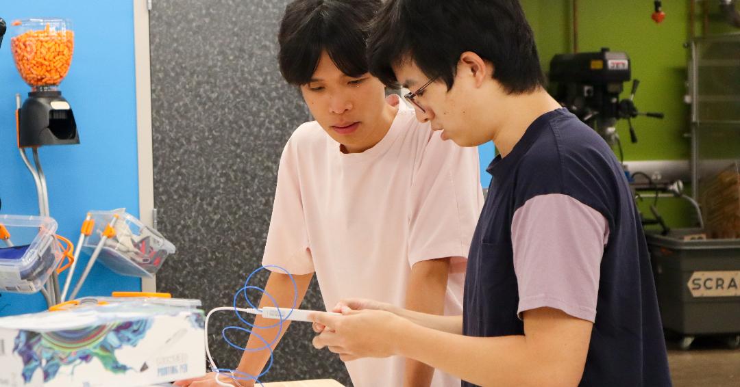 Two people loading a 3D printer pen